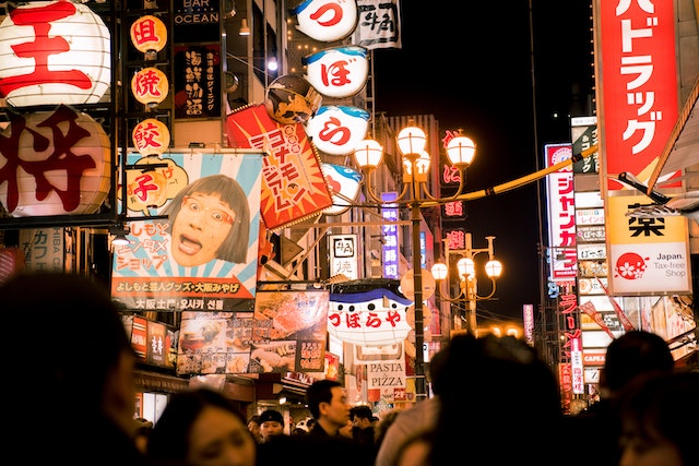 Nightime view of a bustling city in Japan, with modern and traditional illuminated signage.